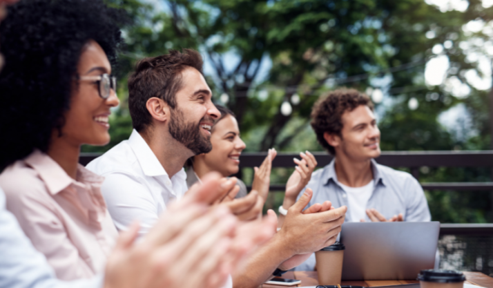 Groupe de personnes installé sur une table en extérieur applaudissant