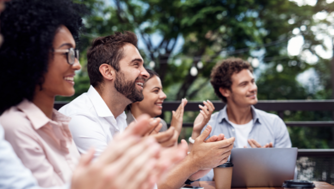 Groupe de personnes installé sur une table en extérieur applaudissant